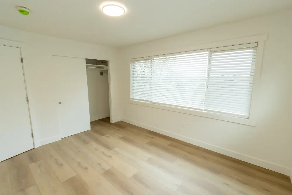 Updated bedroom with new flooring, paint, lighting, and window coverings.
