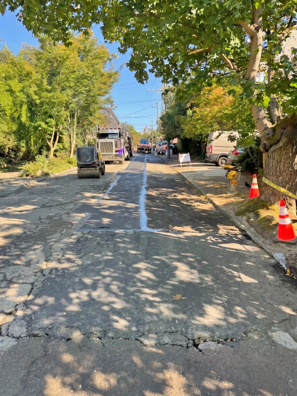 Final asphalt paving over underground electrical trench with roller and sealed joints