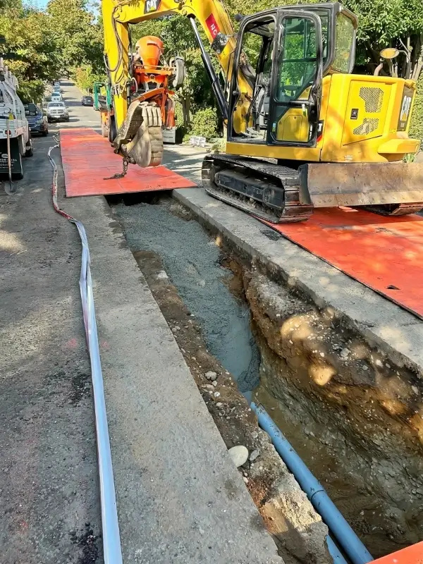 Underground power conduit with concrete encasement in urban trench.